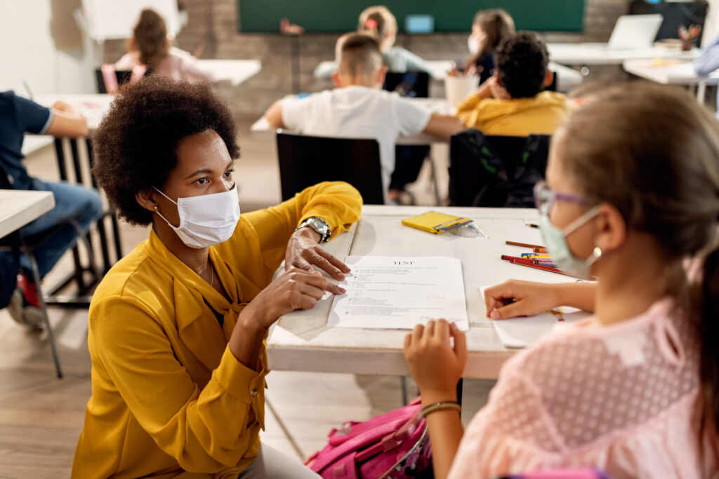 Teacher and schoolgirl wearing protective face masks